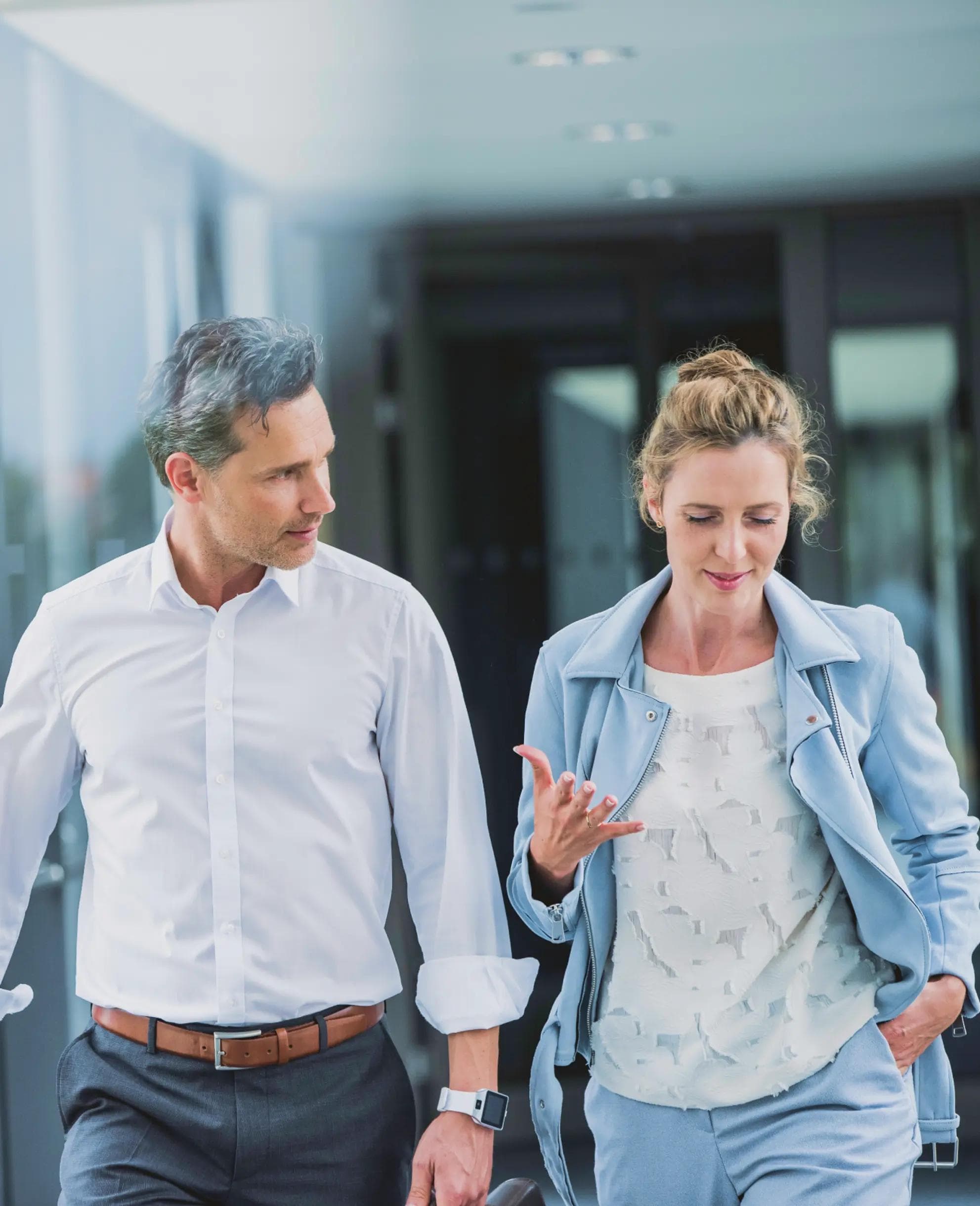 A man and a woman are walking down a hallway.