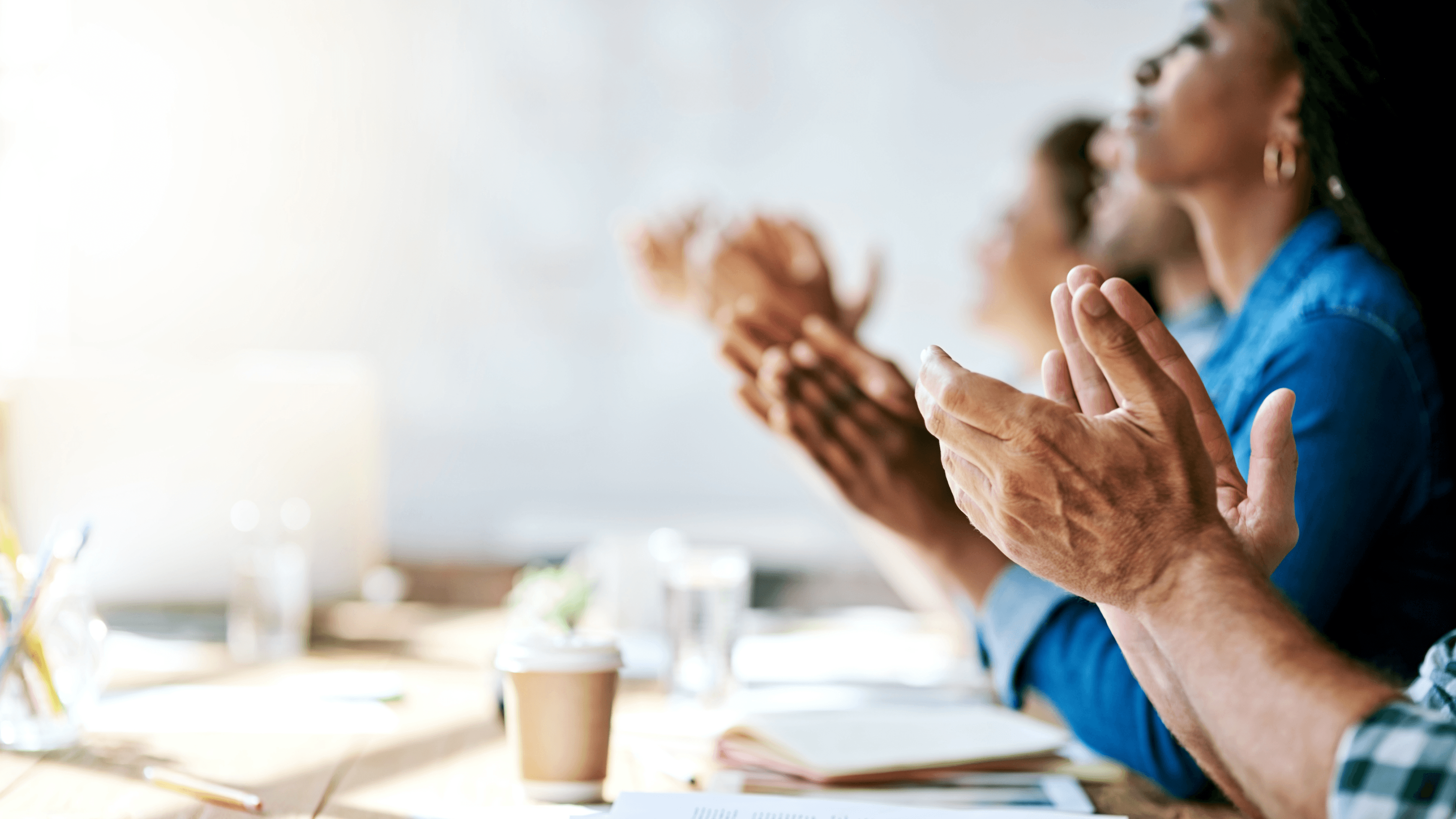 People clapping at work desk.
