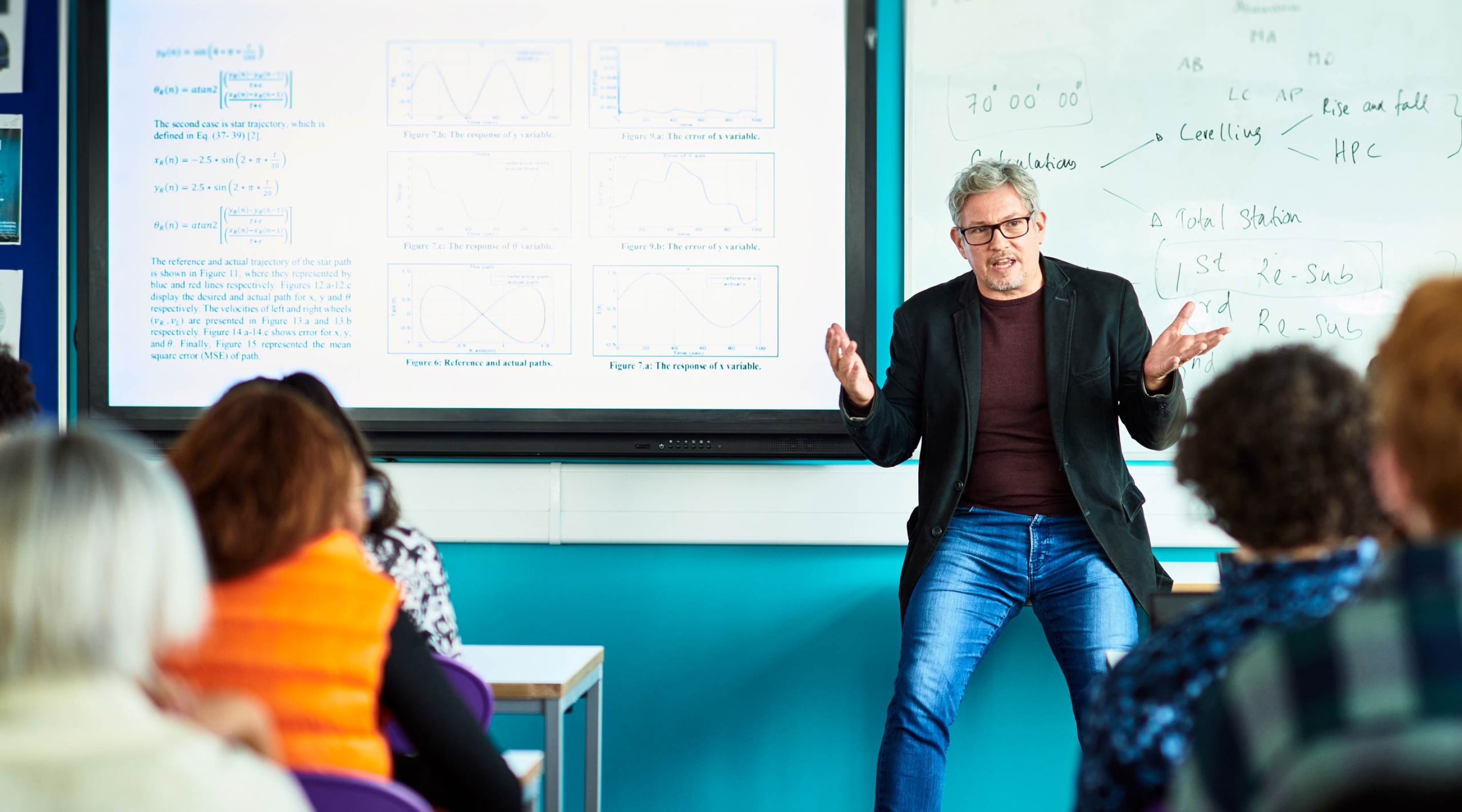 A man is giving a presentation to a group of people in a classroom .